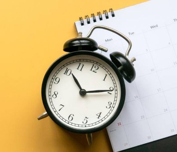 Analog clock sitting on desktop with calendar