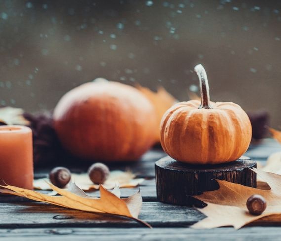 Pumpkin sitting on picnic table with leaves and fall candle