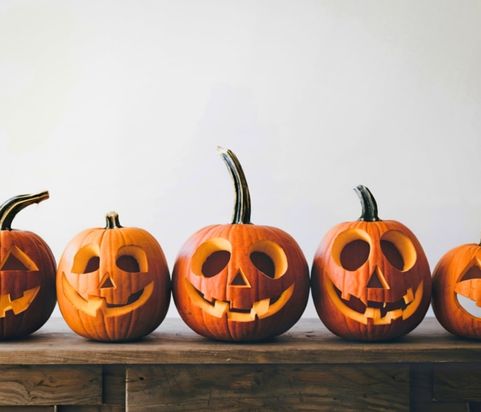 Five jack-o-lantern pumpkins sitting on wooden desk