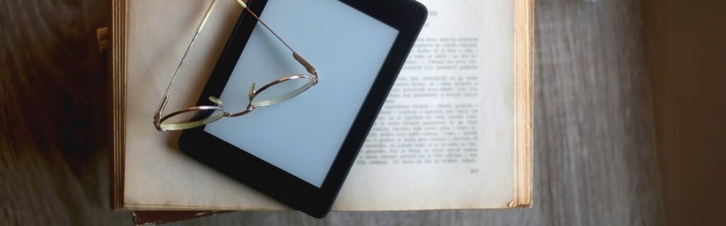 Book with an e-reader tablet and glasses on top of it
