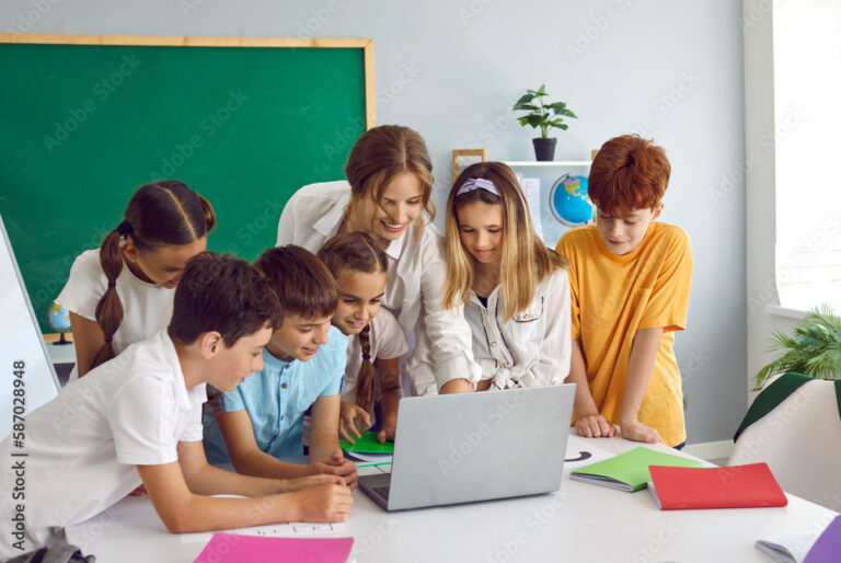 Teacher instructing a group of middle school aged students using a laptop