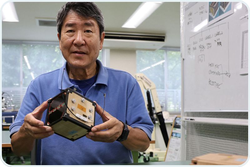 former astronaut Takao Doi holds a model of the wooden LignoSat satellite.
